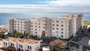 Ein mehrstöckiges Hotel mit Blick auf das Meer, einem Parkplatz und einer Fußgängerzone.