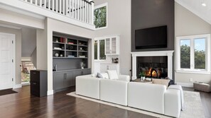 Una sala de estar moderna con chimenea, un sofá blanco y una unidad de entretenimiento integrada.