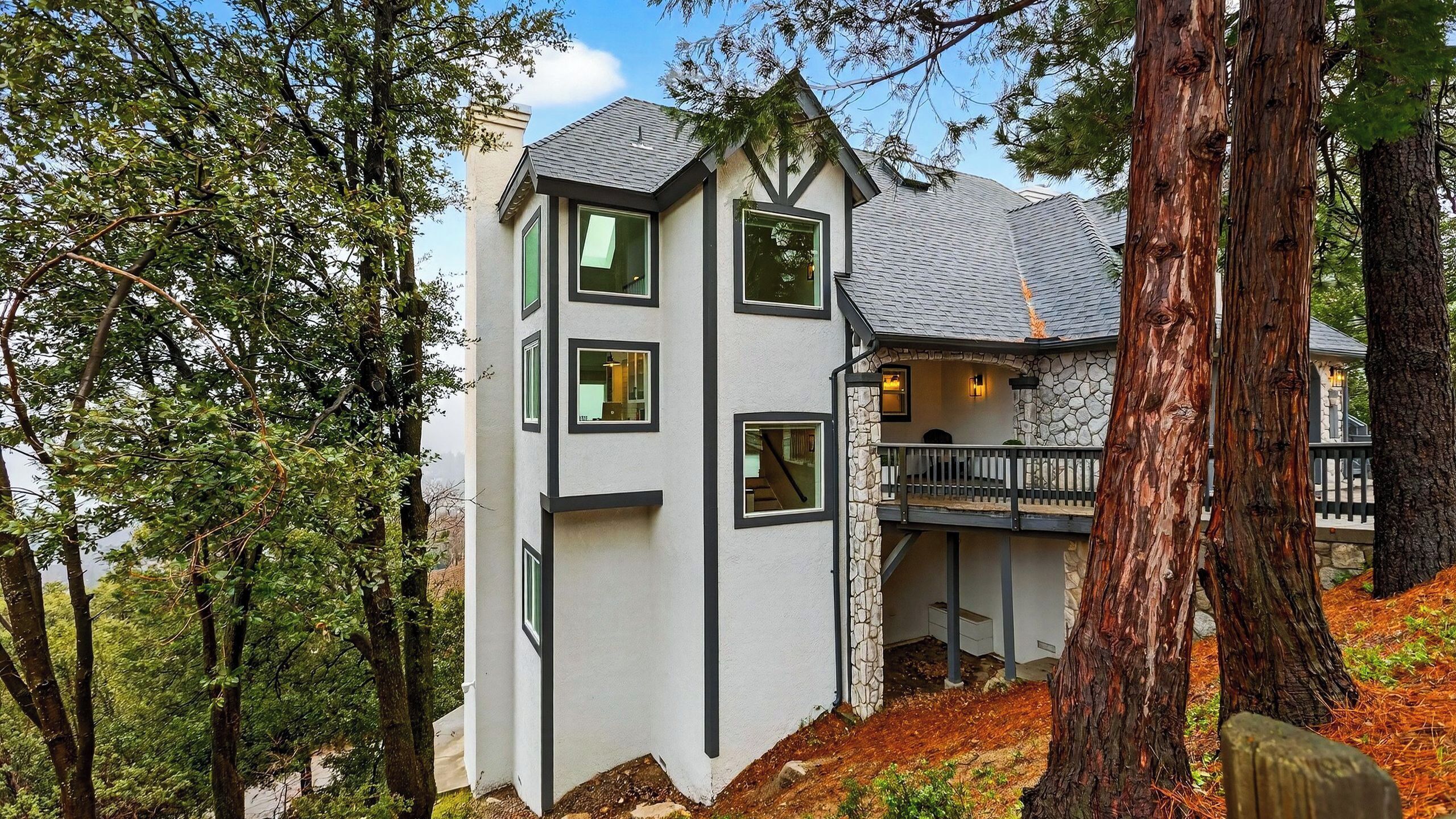 A modern house with a stone facade, multiple windows, and a balcony.