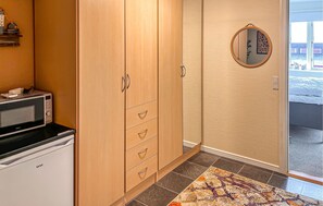 A hotel room with a kitchenette, a large wardrobe, a round mirror, and a patterned rug. - Beautiful home in Aabenraa with WiFi (Aabenraa)