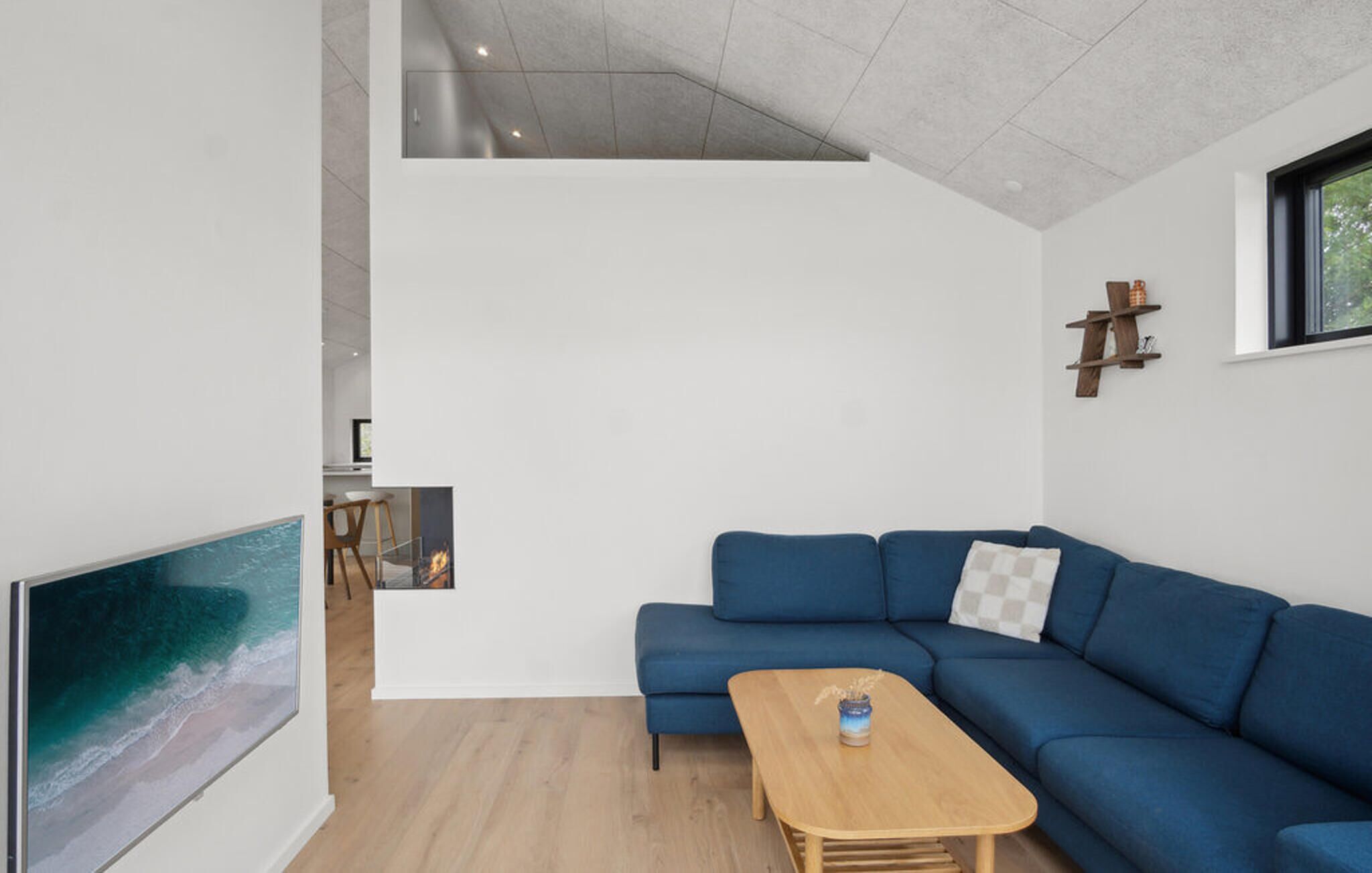 Ein modernes Wohnzimmer mit einem blauen Sofa, einem Holztisch und einem großen Fernsehbildschirm.