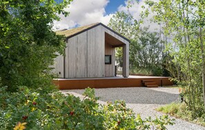 Un bâtiment moderne doté d’un toit en pente, entouré de verdure et de gravier.