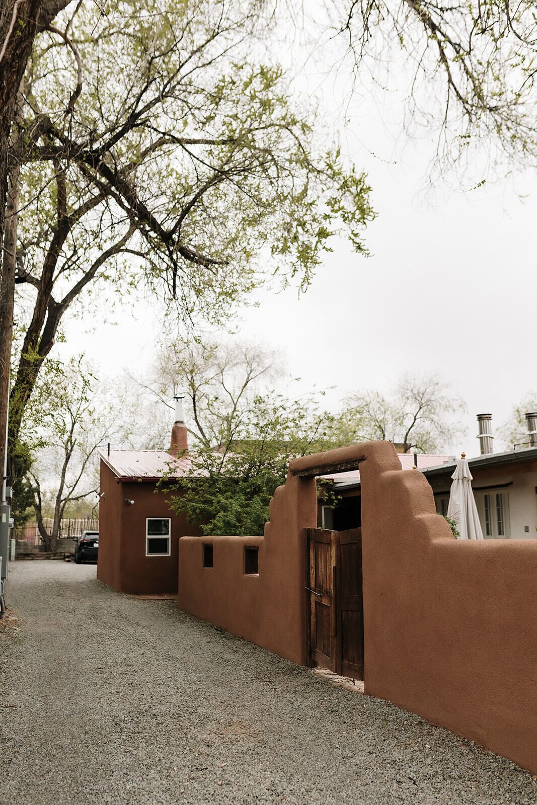 A rustic building with a gravel driveway and a wooden door.