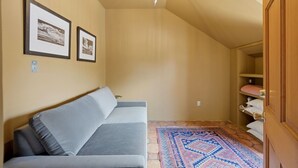Ein gemütliches Zimmer mit einer Couch, einem gemusterten Teppich und einer Holztür.