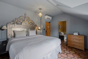 Ein Schlafzimmer mit einem großen Bett, einem Holzkapillon, einer Klimaanlage und einem gemusterten Kopfteil.