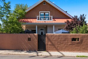Une maison à deux étages avec un balcon, une porte d’entrée et une entrée fermée par un portail.