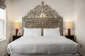 Une chambre d’hôtel avec un grand lit, deux lampes de chevet et une tête de lit décorative.