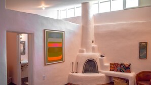 Una habitación acogedora con chimenea, un tapete colorido y un cuadro abstracto grande.