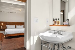 Een hotelkamer met een bed, een badkamer met een wastafel en spiegel, en toiletartikelen op het aanrecht.