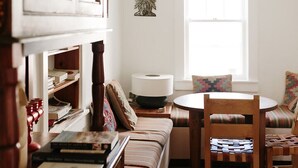Een gezellige woonkamer met een houten bank, een ronde tafel en een boekenkast vol boeken.