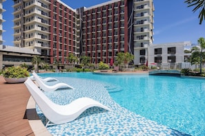 A modern hotel with a large pool area, including lounge chairs and a tiled deck. - Elegant Wood-accent Studio With Balcony (Lapu-Lapu)