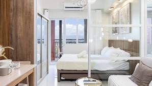 Una habitación de hotel moderna con una cama grande, un separador de vidrio, una pared de acento de madera y vistas a la ciudad.