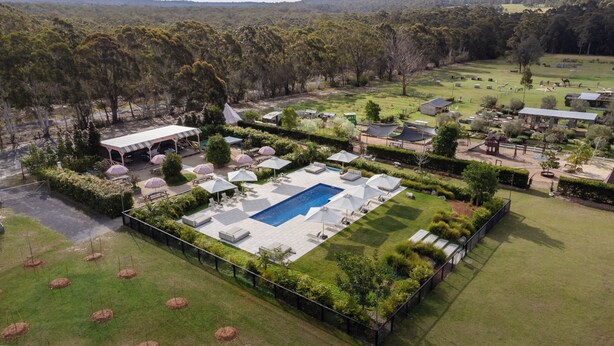An aerial view of a resort with a swimming pool, outdoor seating, and a large covered area. - The Woods Farm (Tomerong)