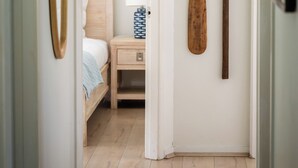 A hallway with a bed, a small bedside table, and wooden paddles on the wall. - The Woods Farm (Tomerong)