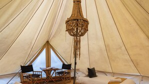 A tent with a bed, two chairs, a table, and a hanging light fixture. - The Woods Farm (Tomerong)