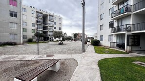 Un edificio residenziale con numerosi balconi, uno spazio aperto centrale con una panchina e una piccola area verde.