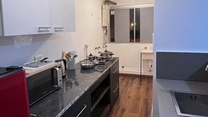 Una cucina compatta con isola centrale, pavimento in legno e mobili bianchi.