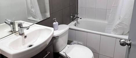 A modern bathroom with a sink, toilet, and bathtub.
