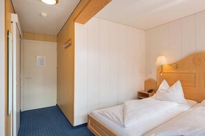 Une chambre d’hôtel avec un lit, une table de chevet, une lampe et une porte.