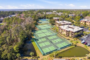 A tennis court complex surrounded by residential buildings and a body of water.
