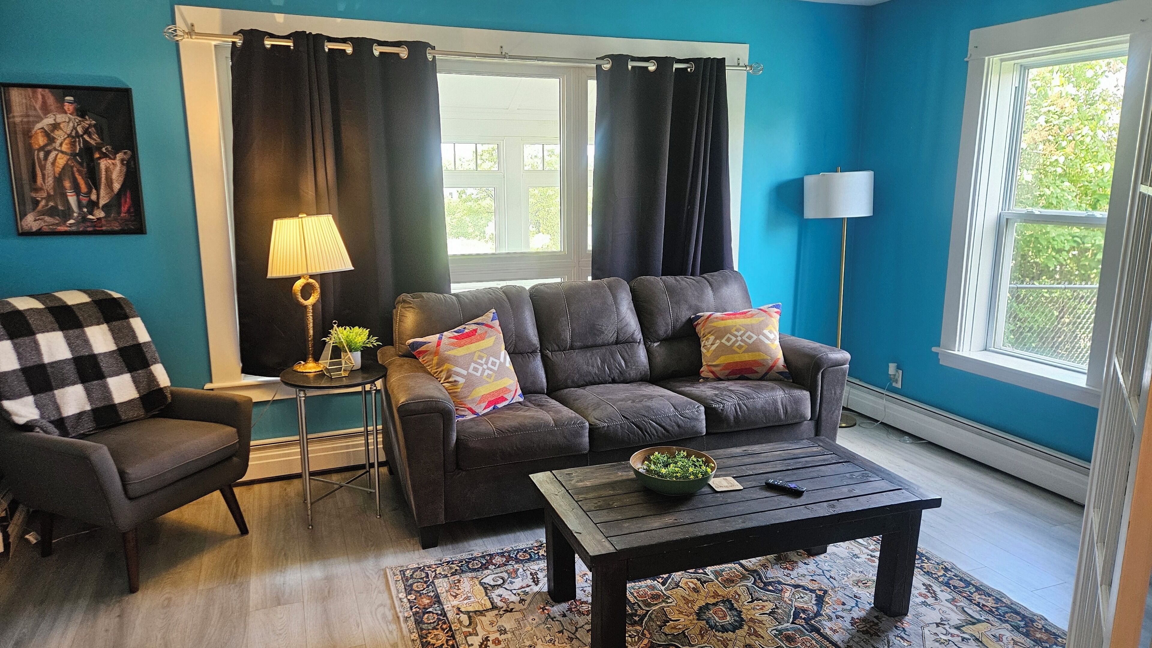 A living room with a sofa, armchair, coffee table, and a rug.
