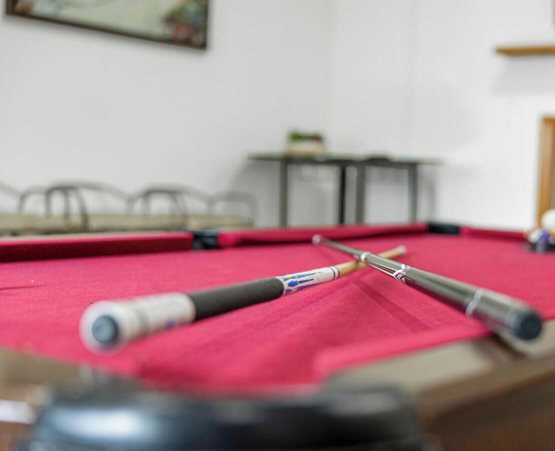 A pool table with two cues and a red felt surface.