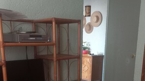 Une pièce dotée d’un meuble de rangement en bois pour les appareils multimédias, d’un téléviseur et d’un sol carrelé.