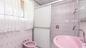 A bathroom with a pink sink, toilet, and shower area.