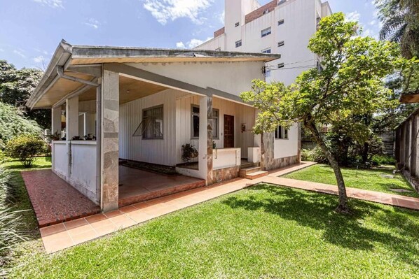 Une maison moderne dotée d’un patio couvert, d’une pelouse bien entretenue et, en arrière-plan, d’un grand immeuble.
