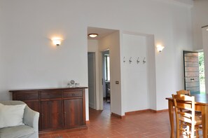 Un'ampia zona giorno con un armadio in legno, un tavolo da pranzo con sedie e un corridoio che conduce a un'altra stanza.