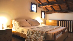 Un dormitorio con una cama de madera, un mesita de noche, un aparador y una ventana con cortinas.