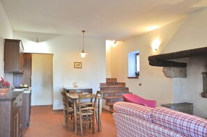 A kitchen with a dining table and chairs, a staircase, and a red checkered sofa. - Villa i Noccioli   18 sleeps, swimmingpool, estate (CAPRANICA)