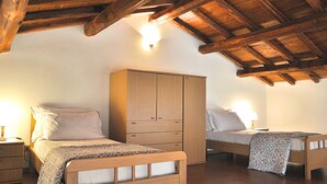 Ein Schlafzimmer mit zwei Holzbetten, einem Kleiderschrank und einer geneigten Decke mit freiliegenden Balken.