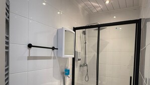 Une salle de bain moderne équipée de toilettes, d’un lavabo et d’une douche à parois de verre.