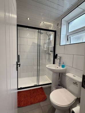 A modern bathroom with a glass-enclosed shower, a white sink, and a toilet. - Araan House Hotel -Families and Couples Only (Blackpool)