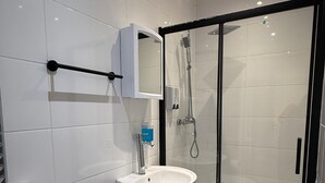 Une salle de bain moderne équipée de toilettes, d’un lavabo et d’une douche à parois de verre.