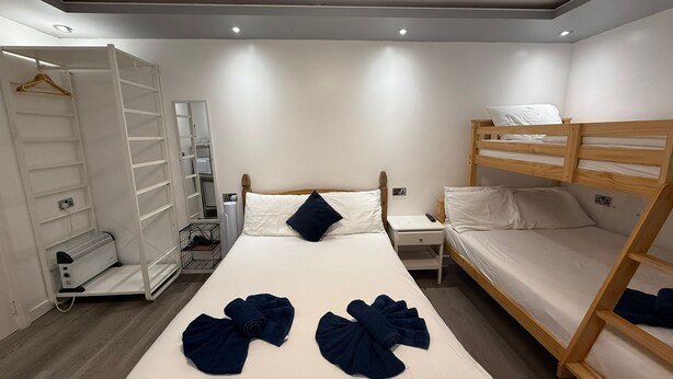 Une chambre d’hôtel avec un lit superposé, un lit simple, une armoire et un miroir.