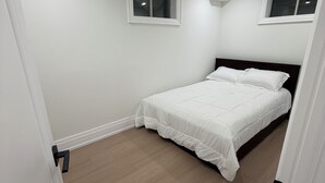 Un dormitorio con una cama, dos ventanas y una puerta.