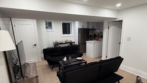 Una sala de estar moderna con un sofá negro, una mesa de centro y una mesa de comedor.