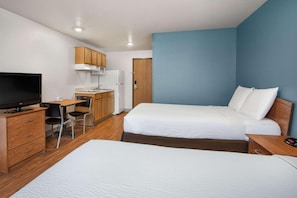 A hotel room with a bed, a desk, a television, and a kitchenette. - Woodspring Suites Clarksville Ft Campbell (Clarksville)