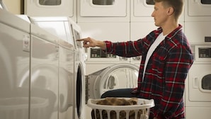 Une personne utilisant un lave-linge à chargement frontal dans une laverie en libre-service équipée de plusieurs machines.