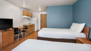 Une chambre d’hôtel comprenant un lit, un bureau avec une chaise, une télévision et une kitchenette.