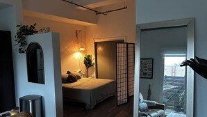 A bedroom with a bed, bedside table, lamp, and a sliding shoji screen. - Cozy studio apartment in charming St. Petersburg perfect for your getaway. (St. Petersburg)