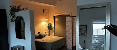 A bedroom with a bed, bedside table, lamp, and a sliding shoji screen.