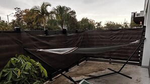 A rooftop terrace with a hammock, a patterned mat, and a chair. - Cozy studio apartment in charming St. Petersburg perfect for your getaway. (St. Petersburg)