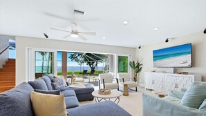 A spacious living room with a large gray sectional sofa, a light blue armchair, and a white entertainment unit with a flat-screen TV. - Punta Gorda Harbor View Vacation Home - Waterfront Home with Private Pool (Punta Gorda)