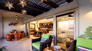 Un espace patio accueillant, avec des meubles en osier, une table à manger et une vue sur le salon.
