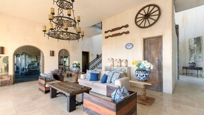Un vaste espace de vie agrémenté d’une table basse en bois, d’un canapé avec des coussins à motifs et d’un mur décoratif orné d’une grande roue.