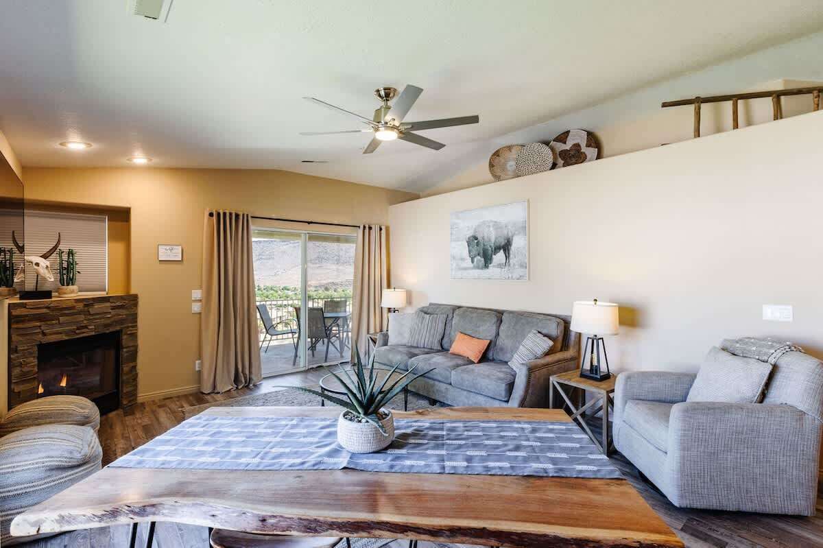 Ein Wohnzimmer mit Kamin, Deckenventilator, Sofa, Couchtisch und Esstisch.