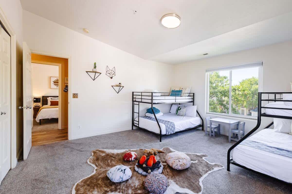 A bedroom with bunk beds, a desk, and a large window.